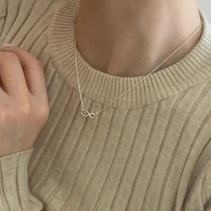 Minimalist 925 sterling silver infinity pendant necklace worn on a striped sweater