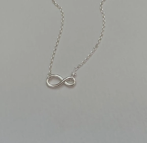 Detail of 925 sterling silver infinity pendant with small sparkling zircon stone