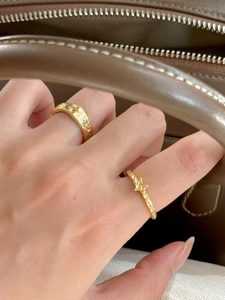 Detail of gold star motif rings with zircon and pearl texture on a hand with luxury bag