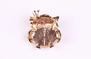 Macro view of the golden owl brooch back with safety pin and textured metal finish