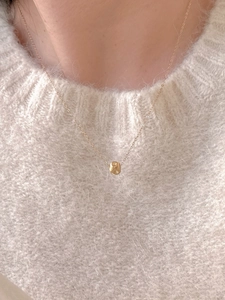Close-up of a 925 sterling silver gold-plated square necklace on a beige sweater
