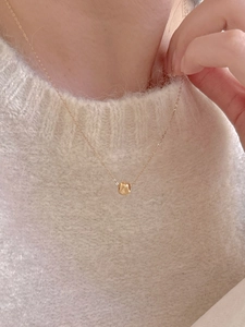 Close-up of minimalist gold 925 sterling silver square pendant necklace worn on a sweater
