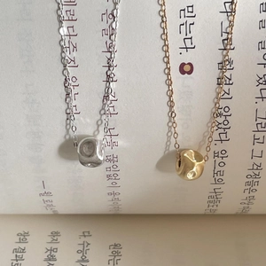 Detail of gold and silver textured cylinder pendant necklaces on book pages