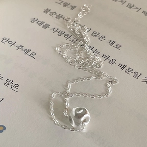 Minimalist 925 sterling silver necklace with textured cube pendant on a book page