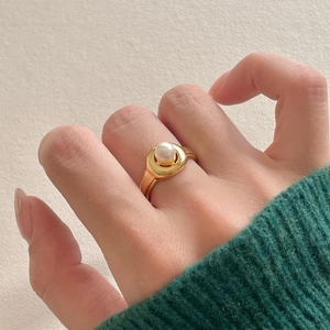 Detail shot of a vintage pearl ring in golden finish worn on a middle finger