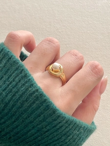 Close-up of minimalist gold-plated wide band ring with a central white pearl detail