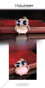 Detailed view of owl ring with opal abdomen and sparkling zircon pave on a vintage book