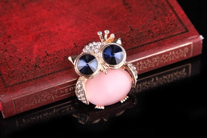 Macro shot of owl brooch with sparkling rhinestones and pink cat eye stone