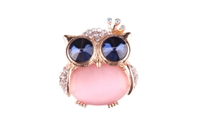 Macro detail of owl brooch with pink opalite belly and sparkling blue crystal eyes