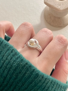 Close-up of minimalist 925 sterling silver ring featuring a white pearl on a finger