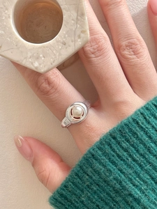 Close-up of 925 sterling silver ring with oval bezel-set pearl on model's finger