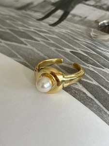 Close-up of golden pearl open ring featuring a thick high-gloss band and elegant white pearl