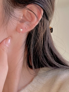Close-up of minimalist white pearl earring and silver stud on a female ear