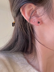 Close-up of minimalist 925 silver stud earrings with black bead on model's ear