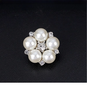 Macro shot of a five-petal flower brooch with white pearls and a crystal centerpiece