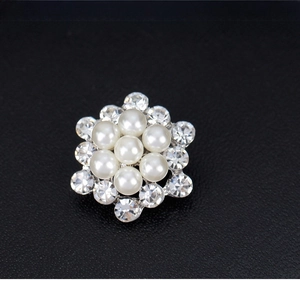 Macro detail of silver floral brooch featuring seven pearls and sparkling rhinestones