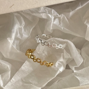 Detailed view of silver and gold heart-shaped cutout rings on soft tissue paper