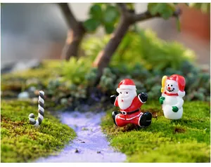 Figurines de Noël miniatures avec Père Noël et bonhomme de neige dans un paysage de mousse