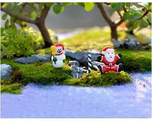 Vue macro de figurines de Père Noël et bonhomme de neige sur mousse décorative