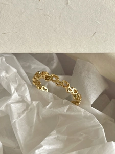 Macro view of gold hollow heart-shaped continuous link ring on premium tissue paper