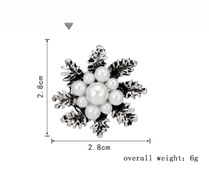 Detail showing a snowflake brooch with white pearls and silver petals measuring 2.8cm