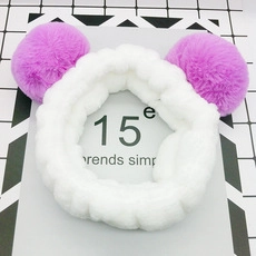 Close-up of a plush white headband with purple pom-poms on a trendy decorative card