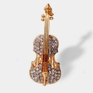 Detailed view of a gold violin brooch with sparkling rhinestones on a grey background