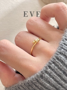 Detail of a 925 sterling silver beaded knot ring with gold finish worn on a finger
