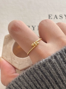Close-up of a minimalist golden knot ring with double beads on a hand display