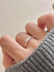 Macro shot of 925 sterling silver minimalist bead ring on a knitted sweater background