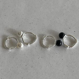 Close-up of 925 sterling silver huggie earrings with black and white pearl beads
