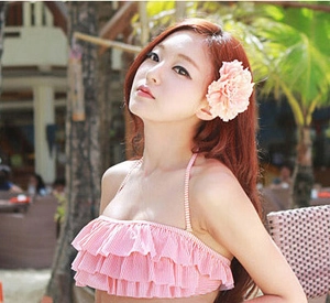 Detail of pink striped swimwear top with ruffle trim worn by a model in tropical setting