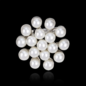 Fashion flower brooch with white pearls and sparkling rhinestones on black background