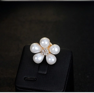 Macro shot of pearl flower brooch with white crystal center and golden metal base