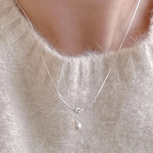 Minimalist 925 sterling silver pearl necklace with a sleek knotted pendant on a model
