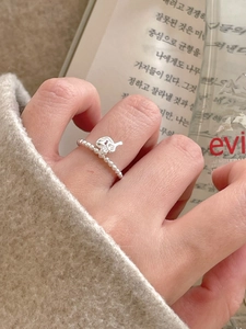 Detail of a minimalist 925 silver beaded heart ring worn by a model in a lifestyle setting
