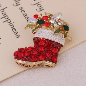 Close-up of a Christmas stocking brooch featuring red and green crystals with white enamel