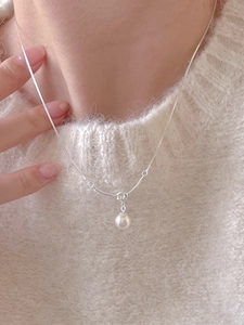 Close-up of a 925 sterling silver knotted pearl pendant necklace worn on a sweater