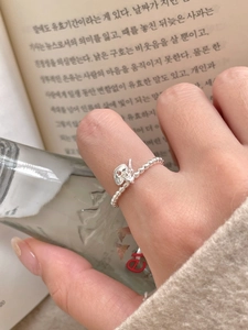 Detailed close-up of a 925 sterling silver beaded ring with a heart pendant on a finger