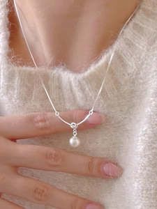 Detail of elegant S925 sterling silver knotted necklace with a white pearl pendant