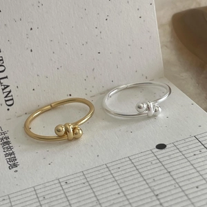 Detailed close-up of polished silver and gold bead knot minimalist open rings