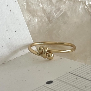 Minimalist 14K gold beaded crossover open ring displayed on a textured stone background