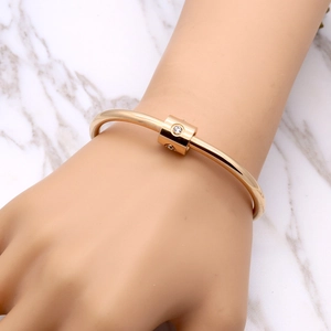 Detailed view of rose gold titanium cuff bracelet with crystal-inlaid cylinder charm on wrist