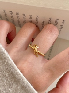 Detail of gold beaded ring with delicate heart lock and key charms on a female hand