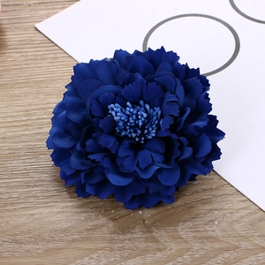 Detailed close-up of blue fabric peony flower hair clip with layered petals on wooden desk