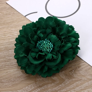 Detail showing layers of a deep green fabric artificial peony flower hair clip for hair
