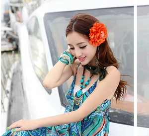 Detail view of a model wearing bohemian turquoise jewelry set and orange floral headpiece