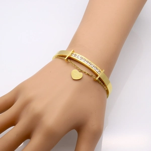 Detail of 18k gold plated stainless steel bracelet with zircon inlay and heart charm
