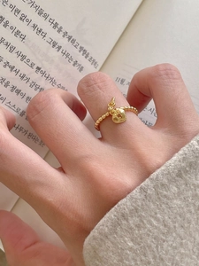 Detail view of a beaded gold ring featuring a delicate heart lock and key charms on a hand