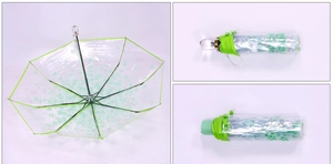Detail view of foldable transparent umbrella featuring green floral patterns and clear handle